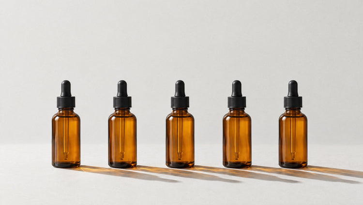 Five amber glass dropper bottles in an evenly spaced row, each casting a long amber shadow.